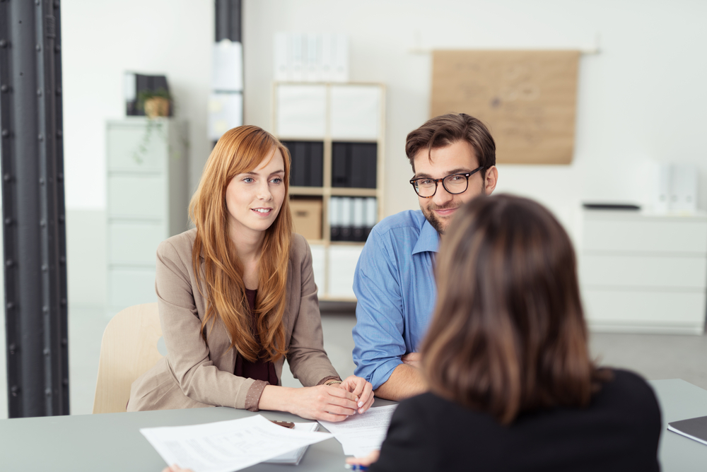 Investment broker meeting with a young couple in her office to discuss their financial needs